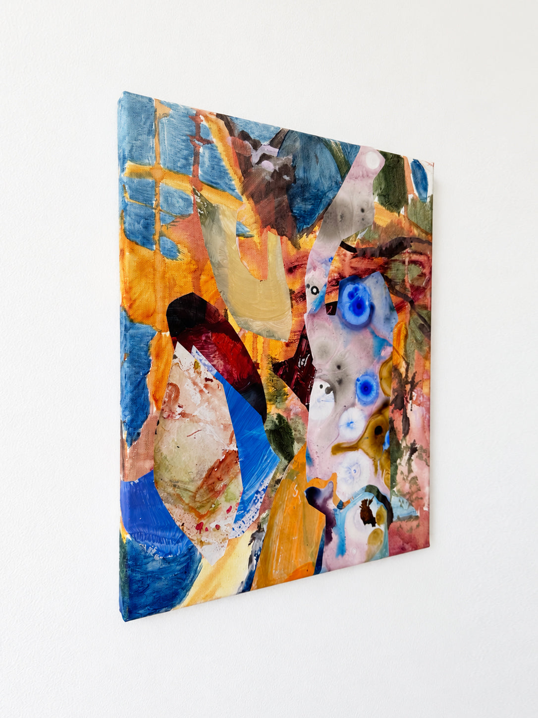Angled view of Between Stone and Water, showing the painted left canvas edge and overlapping blue, ochre and pale marbled fragments.